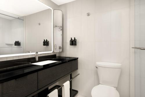 a bathroom with a toilet and a sink and a mirror at Revery Toronto Downtown, Curio Collection by Hilton in Toronto