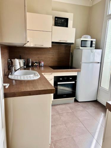 une cuisine avec un évier et un réfrigérateur blanc dans l'établissement Superbe T2 au cœur de Marseille, à Marseille
