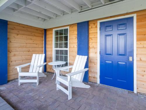 two chairs and a table on a porch with a blue door at Serenity at the Sea in Tybee Island