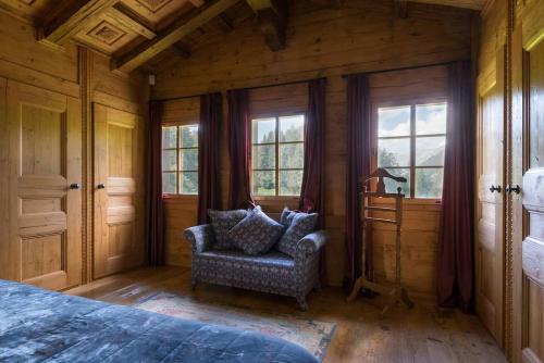 a bedroom with a bed and a chair and windows at Gstaad - Great Luxurious Farmhouse in Kalberhöni