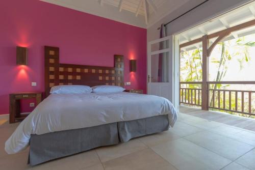 a bedroom with a large bed with a red wall at Tropical Breeze Villa in Domaine du Levant in Petit Cul de Sac