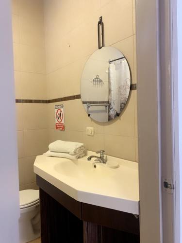 a bathroom with a sink and a mirror and a toilet at Los Soles Suite Mall del Sol Guayaquil Airport in Guayaquil