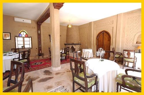 a dining room with tables and chairs and a room with a fireplace at La Rose Du Desert in Erfoud