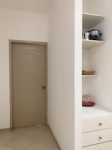 a door in a white room with a shelf at Los Soles Suite Mall del Sol Guayaquil Airport in Guayaquil