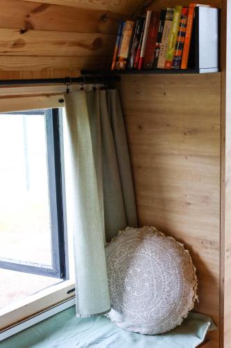 a bedroom with a window with a curtain and a pillow at Oaza Święty Spokój - domek z balią i jacuzzi in Rząśnik