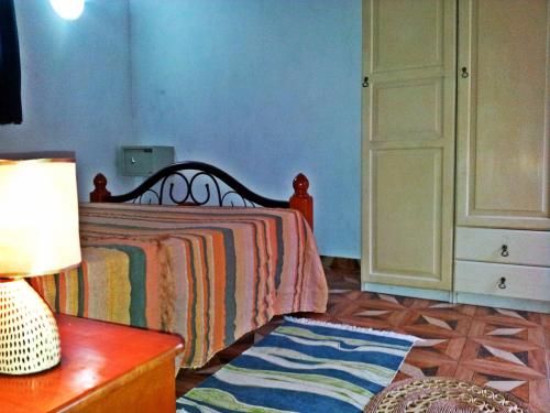a bedroom with a bed and a table with a lamp at La Rocaille in Baie Lazare Mahé