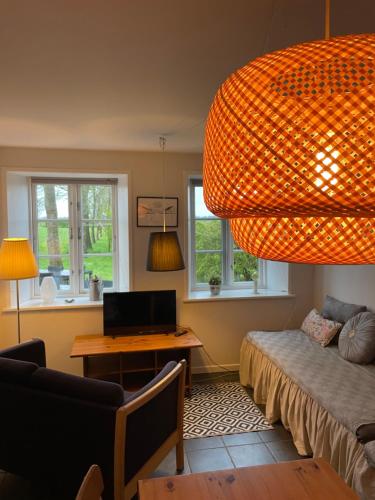 a living room with a desk and a large chandelier at Bremsmaj Farm Holiday in Kværs