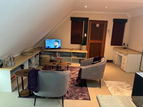 a living room with a table and chairs and a television at Rose Loft in Centurion