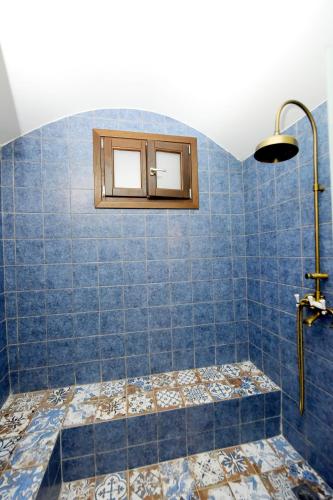 a blue tiled bathroom with a shower with a window at Elaia-Fos in Rhodes Town