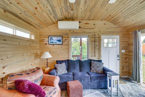 Una sala de estar con un sofá azul y paredes de madera. en Skydance Cabin in Polson, 5 Mi to Flathead Lake!, en Polson