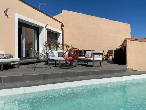 a patio with chairs and a table next to a pool at La Villa des Cistes au calme vue Étangs in Narbonne