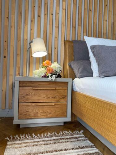 a bed with a dresser with a lamp and flowers on it at LvApart вул Ковжуна 2 кім ізол кухня студія звітні документи in Lviv