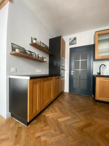 a kitchen with a black refrigerator and wooden cabinets at LvApart вул Ковжуна 2 кім ізол кухня студія звітні документи in Lviv