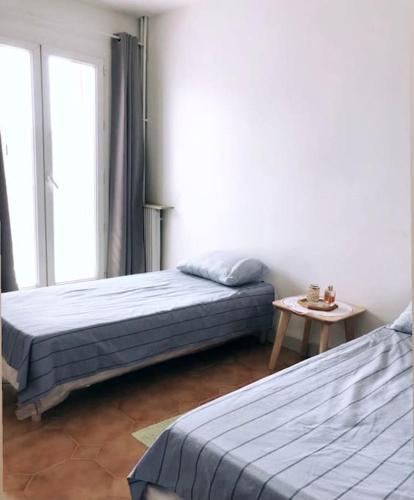 une chambre avec deux lits et une table et une fenêtre dans l'établissement Appartement vue sur mer La Joliette, à Marseille