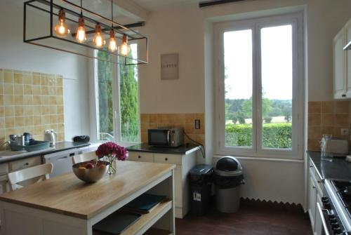 - une cuisine avec une table et quelques fenêtres dans l'établissement Nor14 - Vire - Maison Bear, à Landelles-et-Coupigny