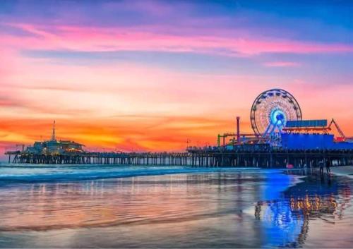 a pier with a ferris wheel on the beach at sunset at Luxurious Hollywood Home City View - Free Parking 10mins to Universal Studios in Los Angeles