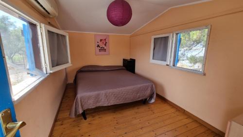 a small bedroom with a bed in a room with windows at BELLA VILLA TRA MARE e LAGO in Sperlonga