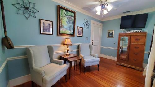 a living room with two chairs and a table and a tv at Pettigru Place Bed & Breakfast in Greenville