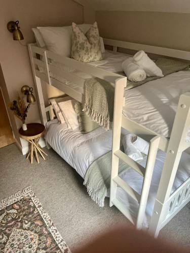 two white bunk beds in a room with a rug at Posh Little Cottage in Llangollen