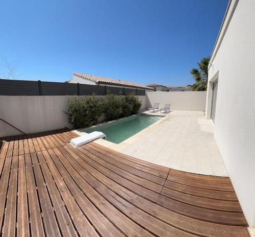 a wooden deck with a swimming pool in a house at Villa moderne et confortable in Béziers