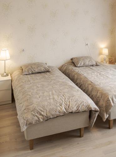 two twin beds in a bedroom with two lamps at Külaliskorter Kärdlas in Kärdla