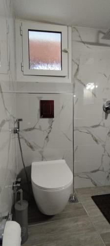 a bathroom with a white toilet and a window at Kaiti Studios 1 in Koukounaries