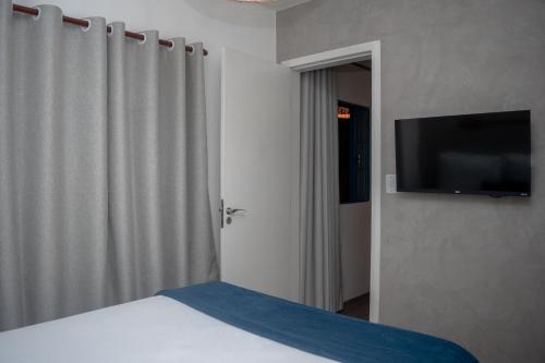 a bedroom with a bed and a flat screen tv at Villa Bella Ferradura in Búzios