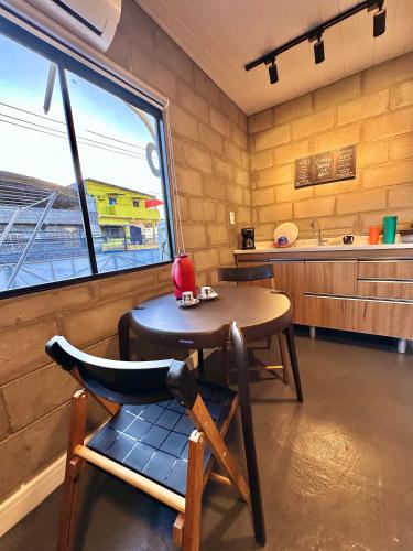 a room with a table and a kitchen with a window at Apto Studio Industrial 07 in Manaus