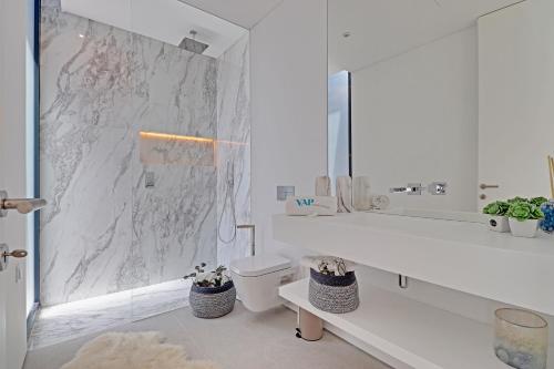 a white bathroom with a toilet and a mirror at One Six Villa in Vilamoura