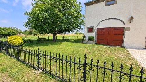 a fence in front of a house with a red door at Gite une belle Histoire in Voisey