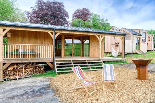a cabin with two chairs in front of it at Les Cabanes Champêtres - Le Domaine des Trois Tilleuls in Villers-la-Ville