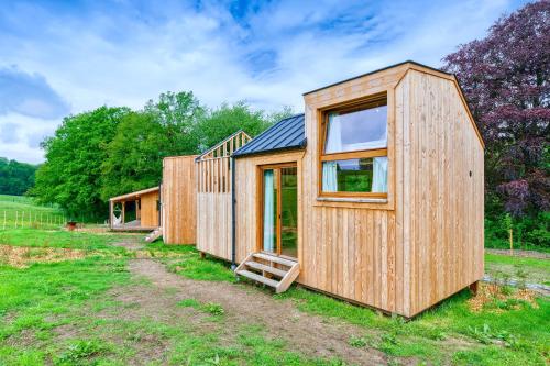 a couple of wooden houses in a field at Les Cabanes Champêtres - Le Domaine des Trois Tilleuls in Villers-la-Ville