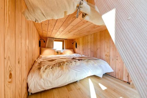 a bedroom with a bed in a wooden room at Les Cabanes Champêtres - Le Domaine des Trois Tilleuls in Villers-la-Ville