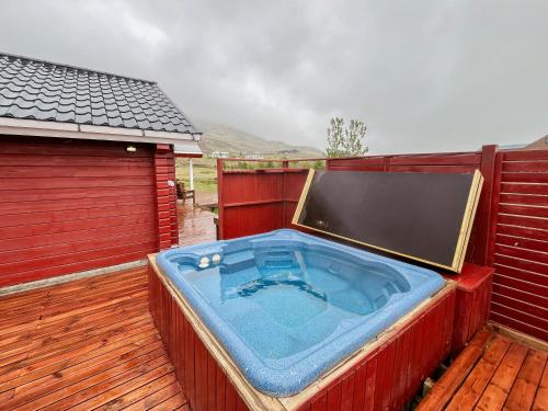 a hot tub on a deck with a red fence at Kololo Cabin in Búrfell