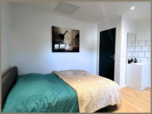 een slaapkamer met een bed en een schilderij aan de muur bij SQ'Appart-y in Saint-Quentin