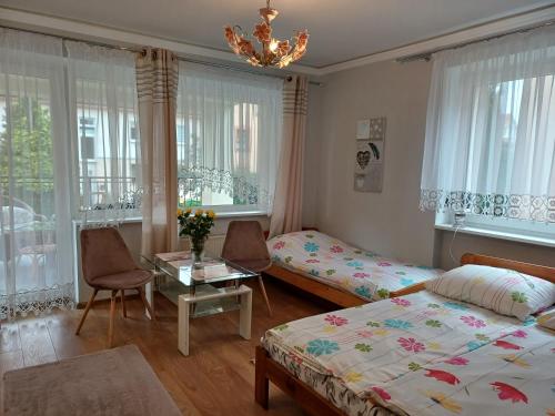 a bedroom with two beds and a table and windows at Morski Brzeg in Świnoujście