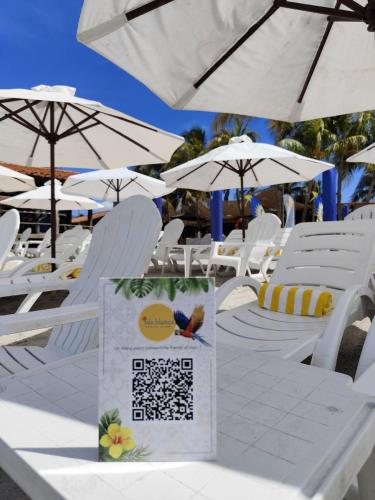 a bunch of white chairs and umbrellas on a beach at Hotel Margarita Village in Porlamar