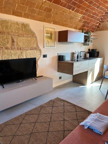 a living room with a flat screen tv and a kitchen at Ermitage la suite-hermitage al tramonto-Hermitage tra le vigne in Cioccaro