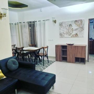 a living room with a black couch and a table at Logement paisible à Mpita in Pointe-Noire