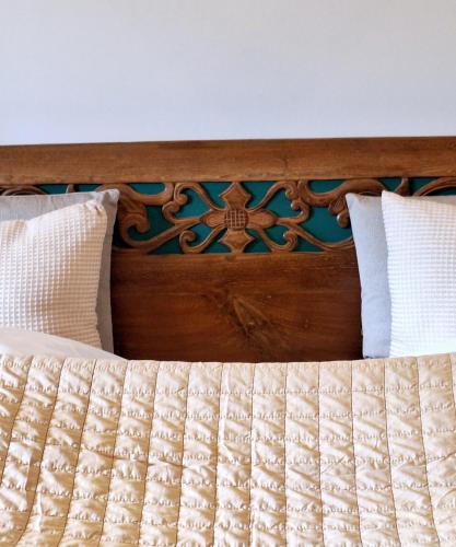 a bed with a wooden headboard and two pillows at Strandhaus Chiemsee in Übersee