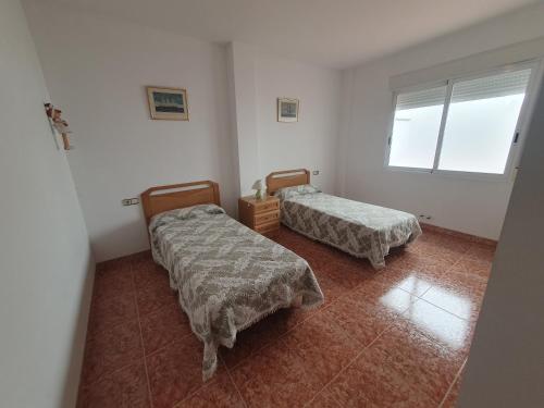 a room with two beds and a window at Apartamento para 6 personas en Alcalá de Xivert in Alcalá de Chivert