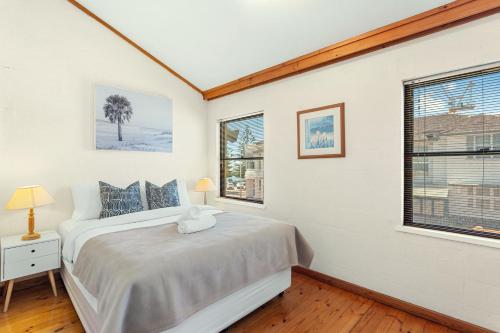 a bedroom with a bed and two windows at 13 Cottesloe - steps from beach - sleeps 3 in Perth