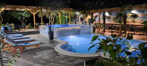 a pool at night with chairs and a table at Holiday home Milicevic in Ljubuški