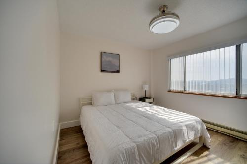 a white bedroom with a bed and a large window at Bright Gadsden Apartment about 10 Mi to Dive Land Park in Gadsden