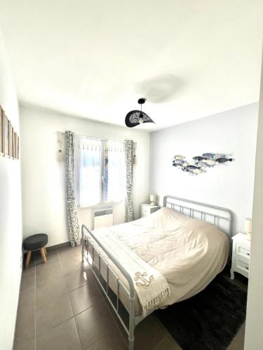 une chambre blanche avec un lit et une fenêtre dans l'établissement maison Oléron, à Saint-Denis-dʼOléron