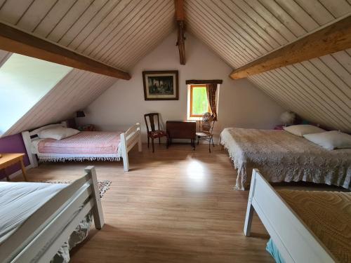 Cette chambre mansardée comprend deux lits et une chaise. dans l'établissement La Grange, à Saint-Père