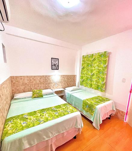 two beds in a room with a window at Bonita in Piranhas
