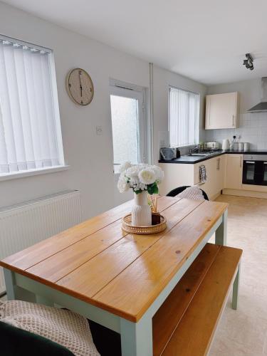 a kitchen with a wooden table with flowers on it at Ty Noah- Home In The Heart Of Pembrokeshire in Milford Haven