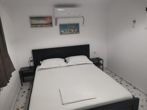 un lit blanc dans une chambre avec deux tableaux au mur dans l'établissement Apartament Casa George Mamaia Nord, à Mamaia Nord – Năvodari
