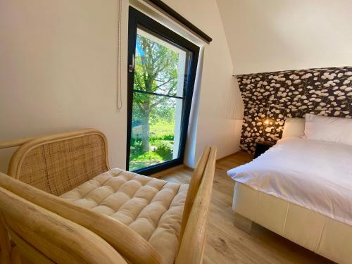 a bedroom with a bed and a chair and a window at Estrella dreams in Amblève